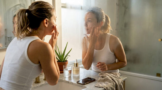 Woman applying skincare in sunlit bathroom