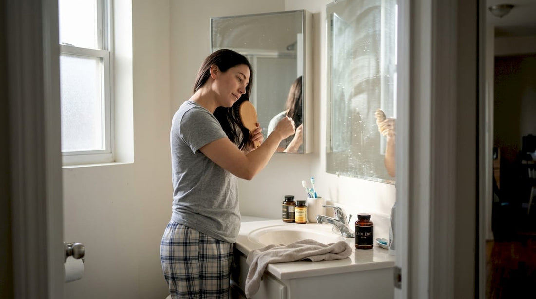 Woman brushing hair near vitamin bottles
