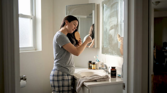 Woman brushing hair near vitamin bottles